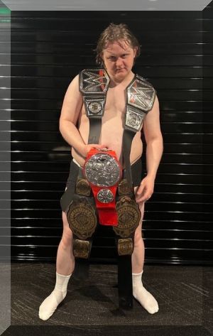 In the absence of an Official Number 1 Single Award as he tours the US, Lewis Capaldi poses with five WWE belts to mark his fifth Number 1 single with Wish You The Best (credit: Official Charts Company) 